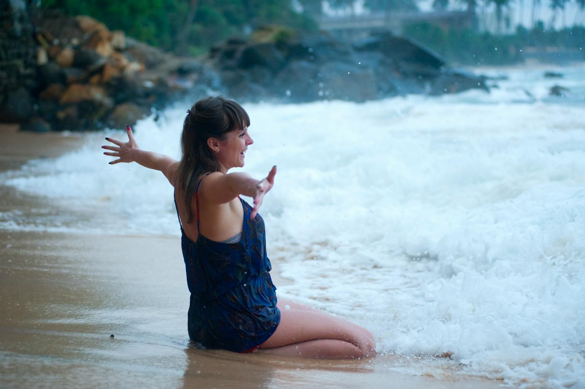 Woman at beach with arms open practicing self-love when it comes to goal setting