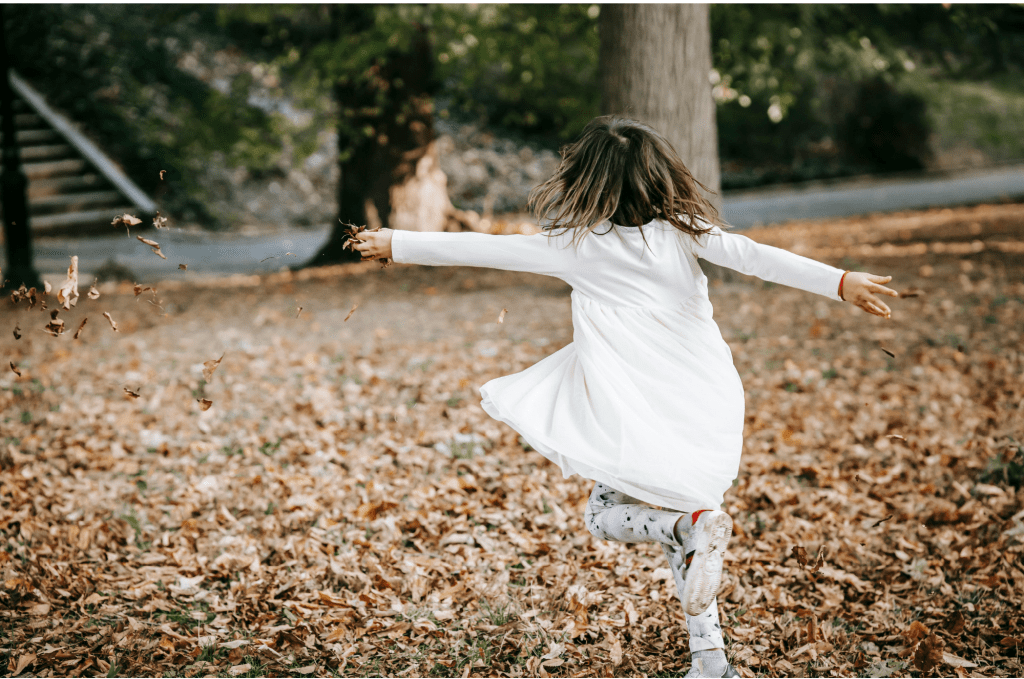 A kid having fun playing in the leaves